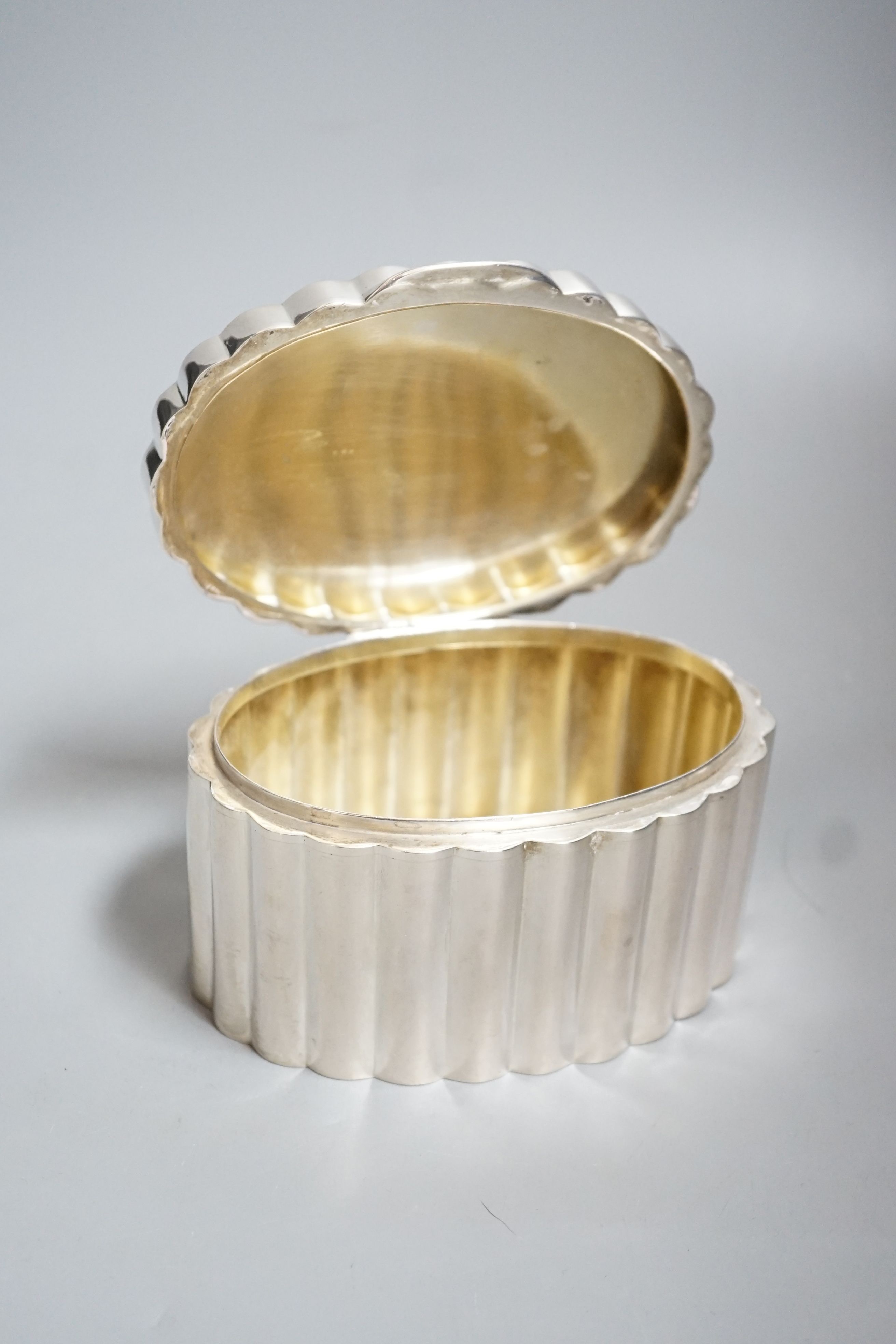 A fluted white metal oval sugar box, 13.3cm.
